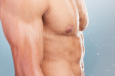 Closeup of man in the shower. Man standing under water with chest and stomach exposed. Naked man washing his body. Muscular man cleaning. Male model showering in studio. Male bodycare routine.