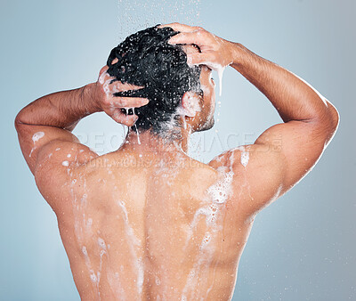 Buy stock photo Closeup of young man washing his hair with shampoo in shower against a blue background. Mixed race man lather shampoo and rinsing it while taking a hot shower. Morning self-hygiene and body care routine