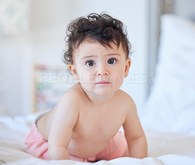 One caucasian baby girl playing alone on the bed at home in day or morning looking to the camera copyspace childhood and growing up concept
