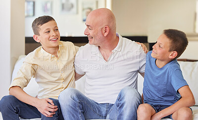 Caucasian man and his two sons sitting on the sofa at home. Happy family of three in the living room. Two brothers sitting with their dad. Smiling, bonding and spending quality time together