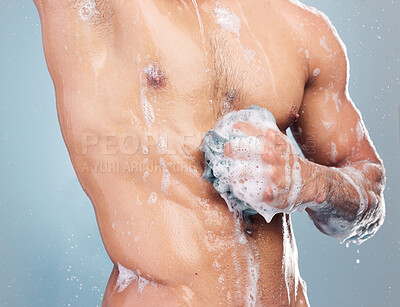 Buy stock photo Closeup of man in the shower. Man rubbing soap on his stomach. Naked man washing his body with a loofah. Muscular man cleaning his body. Male model showering in studio. Man hygiene body care routine