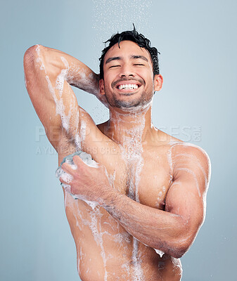 Buy stock photo Muscular young mixed race man smiling taking a warm shower against a blue studio background. Happy hispanic guy washing hair and body with soap under clean running water for good hygiene