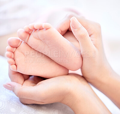 Mother holding baby feet. Closeup of tiny newborn baby feet held by a parent. Small baby toes. Little baby lying on a bed. Woman holding feet of little baby girl. Innocent infant being held by mother