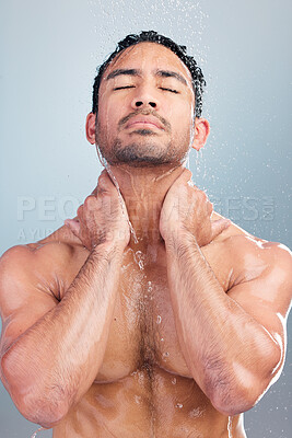 Buy stock photo Serious muscular asian man showering alone in a studio and washing his hair against a blue background. Fit and strong mixed race man standing under pouring water. Hispanic athlete enjoying hot shower