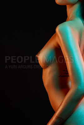 Closeup of female nude body. Beautiful and sexy young mixed race woman posing seductively in studio isolated against a black background. The female body is a work of art
