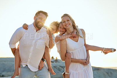 Buy stock photo Carefree caucasian family walking and having fun together on the beach in summer. Parents giving their daughter and son a piggyback on holiday. Little siblings relaxing with their parents on vacation