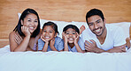 Happy family in bed. Portrait of a young hispanic family in bed. Young mixed race family of four. Two parents bonding with their daughters at home. Sisters relaxing with their mother and father