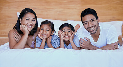 Buy stock photo Happy family in bed. Portrait of a young hispanic family in bed. Young mixed race family of four. Two parents bonding with their daughters at home. Sisters relaxing with their mother and father