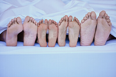 Buy stock photo Mixed race closeup shot of family lying in bed showing their feet only under a clean white blanket and resting on a big comfortable bed. Unknown family relaxing and being lazy against bright copyspace
