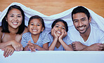 Happy family in bed. Portrait of hispanic family in bed. Young family under a bedsheet. Two parents bonding with their daughters.Sisters relaxing with their parents. Family lying in bed
