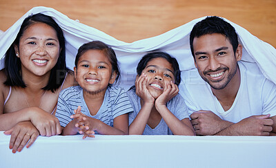 Buy stock photo Happy family in bed. Portrait of hispanic family in bed. Young family under a bed sheet. Two parents bonding with their daughters.Sisters relaxing with their parents. Family lying in bed