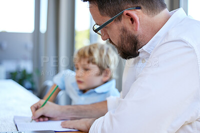 Buy stock photo Young homeschool little boy sitting with his father at the kitchen table. Caucasian male single parent checking his son's homework and grading his paper at the kitchen table in a bright room 