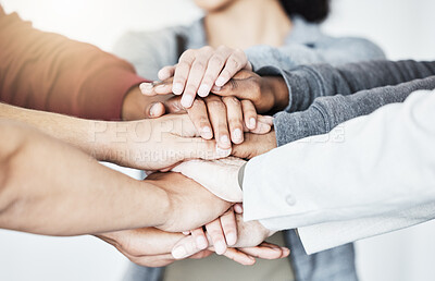 Buy stock photo Group of businesspeople stacking their hands in support with their colleagues standing in a meeting in an office at work. Businesspeople piling their hands for motivation and success together