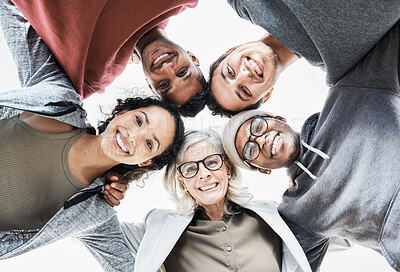 Buy stock photo Low angle portrait of a cheerful group of diverse business people standing huddled together in their office. We make one 
 happy dynamic team.
