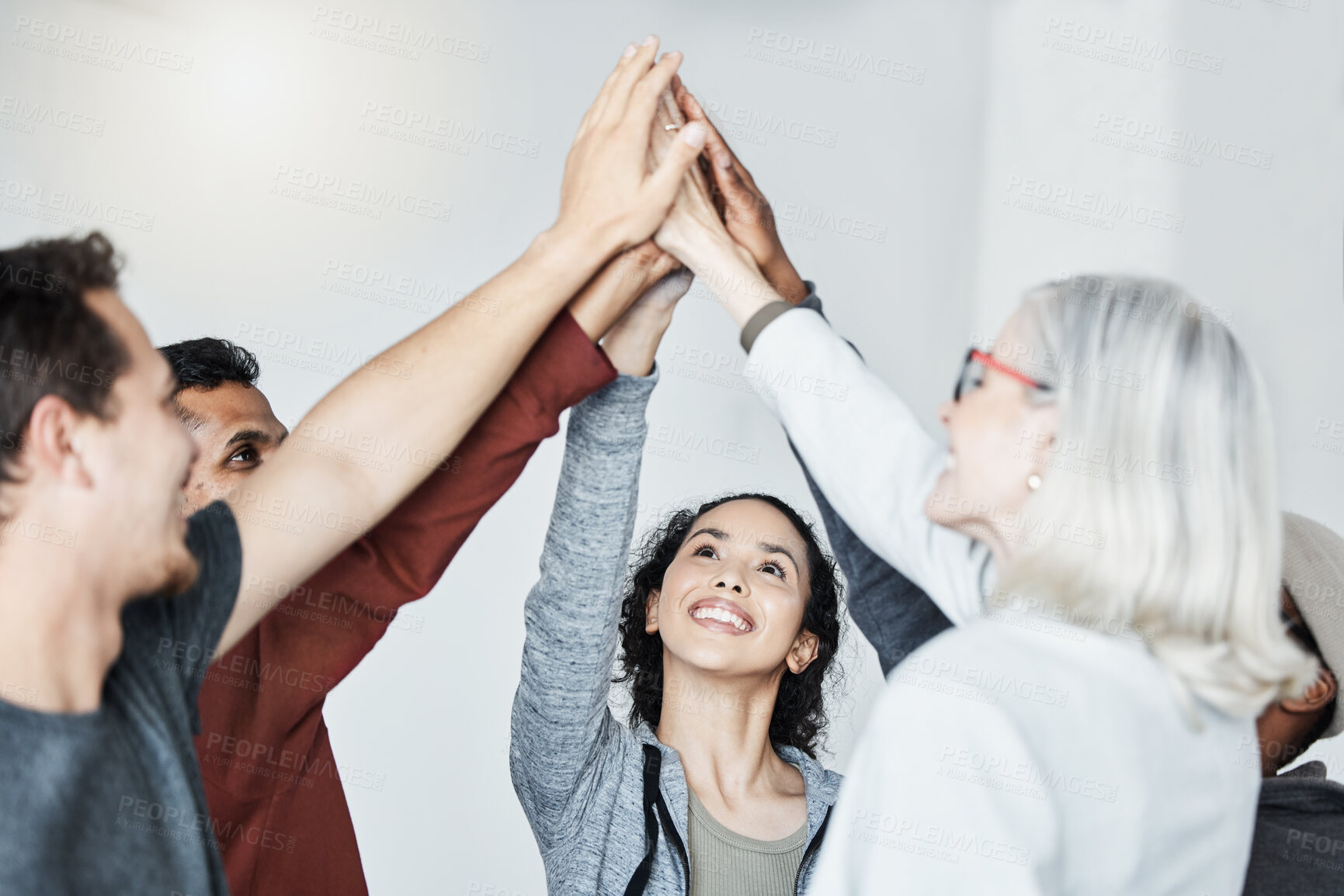 Buy stock photo Diverse group of people standing together in circle and raising their hands in middle after therapy for a high five. Smiling support group celebrating successful session. Friends support mental health