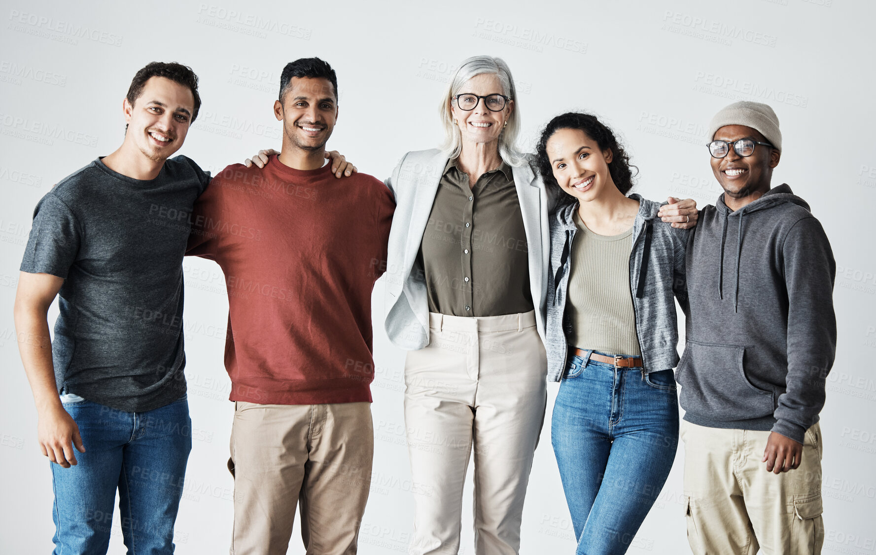 Buy stock photo Portrait of a Team of happy united young business people hugging each other. Diverse mixed race group of men and women standing in row in their office, huddling and smiling all together. Unity and teamwork against a grey background