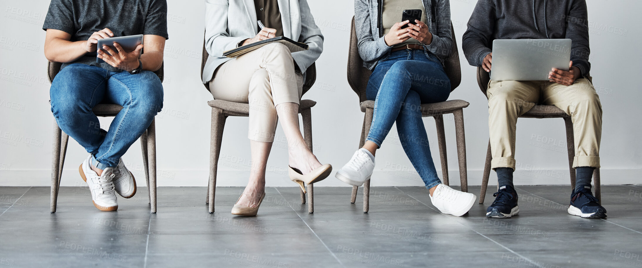 Buy stock photo Candidates sitting on chairs in row using tech devices. Diverse group of applicants waiting for an interview, browsing the internet for interview Q&A. Recruitment agency hiring 