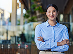 Portrait of a cheerful mixed race smiling businesswoman making with arms folded outside. Young hispanic woman business owner standing outside against blurry copyspace 