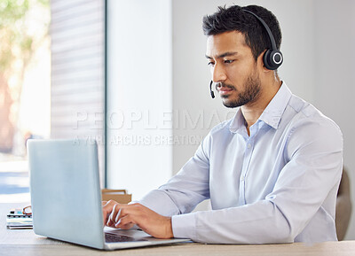 Businessman working in a call center. Operator working on his laptop. Young multiracial man working, wearing a headset. Young businessman working in customer service, on a call.