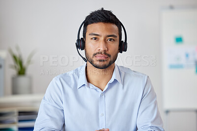 Portrait of a young mixed race businessman working in a call center. Operator at his office job. Hispanic man working, wearing a headset and working in customer service, on a call.