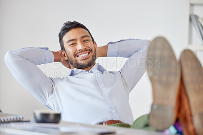 Portrait of a mixed race business man relaxing with his feet up at his desk. Boss looking relaxed and satisfied at workplace. Business success and relaxing in a comfortable work chair