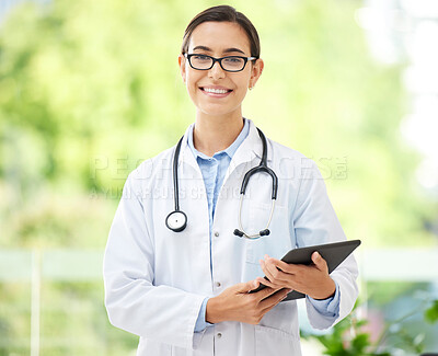 Young female Hispanic doctor wearing a labcoat and smiling while using a digital tablet in her office. Physical health is important to your wellbeing. Mixed race doctor using wireless device at her job in the hospital