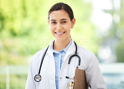 Buy stock photo Confident young mixed race female doctor standing with clipboard a medical office. One hispanic woman in a white coat with stethoscope. Trusted practitioner caring for the health of patients