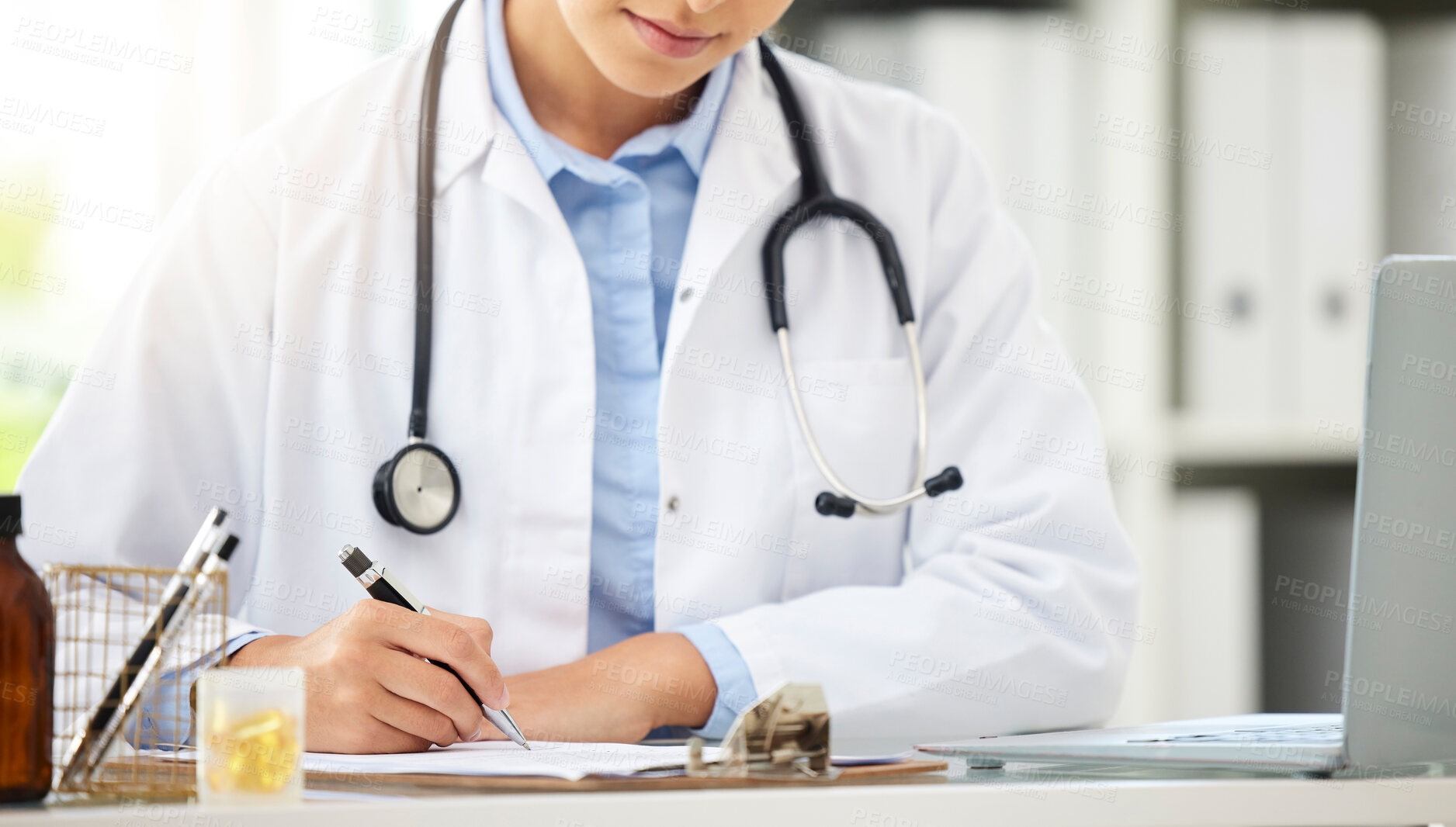 Buy stock photo Planning, doctor writing on a clipboard and with laptop at a desk in a modern office with lens flare. Healthcare, medical research and female nurse or surgeon with stethoscope write notes at work