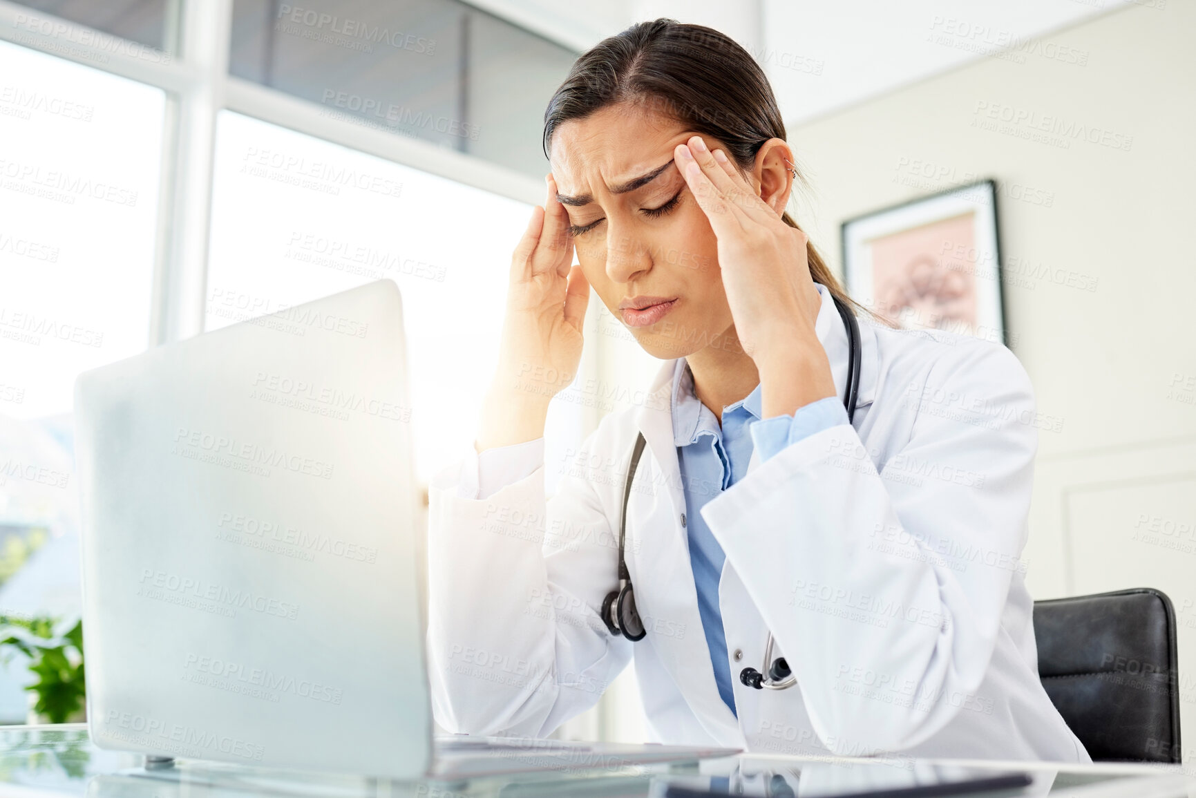 Buy stock photo Mental health, woman doctor with a headache and with laptop at her desk in a workplace office with a lens flare. Stress or depression, problem or mistake and female surgeon sad at her workstation