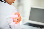 Closeup of shoulder pain highlighted in red. A female doctor holding her arm with an injury. Woman employee working at her desk in a modern office and suffering from a medical problem