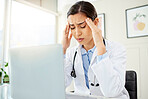 Closeup of a young mixed race doctor looking worried and suffering from a headache while working on a computer in her office. Hispanic female suffering from a head pains and stress at a hospital