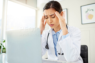 Buy stock photo Closeup of a young mixed race doctor looking worried and suffering from a headache while working on a computer in her office. Hispanic female suffering from a head pains and stress at a hospital