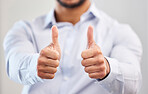 Closeup businessman showing thumbs up in an office. Unknown mixed race professional standing alone and using hand gestures. Hispanic entrepreneur with sign and symbol for good luck, support, endorsing