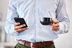 Closeup of male hands holding coffee and smartphone. Businessman using mobile phone to send text, browse social media or use app while on his tea break 