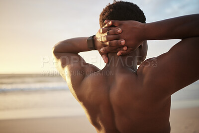 Back of a fit muscle man with hands behind his head, at the beach looking at the view during sunset. Rear view of a fitness guy thinking or bodybuilder staring at the open sky and stretching