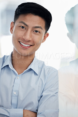 Portrait of one confident young asian business man standing with arms crossed against a glass wall in an office. Happy and successful male entrepreneur showing leadership and motivation in his startup