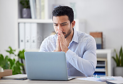 Asian businessman thinking while using his laptop in the office. Mixed race professional sitting alone and feeling contemplative. Entrepreneur finding a solution to a problem while reading an email