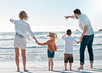Back of family on holiday at the beach. Family pointing to the distance on the beach. Caucasian family on vacation by the sea. Parents bonding with their children on a getaway.