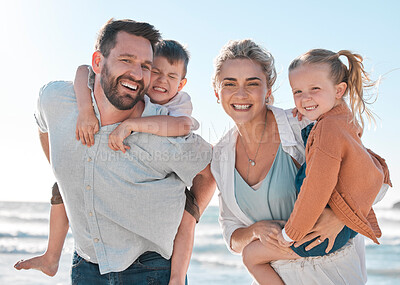 Buy stock photo Happy parents carrying their little children during a day on the beach. Smiling boy and girl enjoying free time with their mother and father. Smiling couple bonding with their children on a weekend