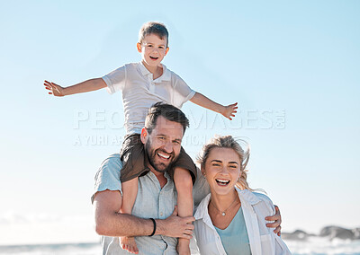 Portrait of happy caucasian parents and playful son having fun in sun against blue sky outside. Carefree dad carrying excited boy on shoulders for piggyback ride and pretending to fly with arms out
