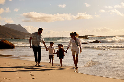 Carefree caucasian family holding hands and running together on the beach. Parents spending time with their son and daughter on holiday. Little siblings on a walk with their parents on vacation