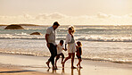 Carefree caucasian family walking together on the beach in the morning. Parents spending time with their son and daughter while on holiday. Little siblings on a walk with their parents on vacation
