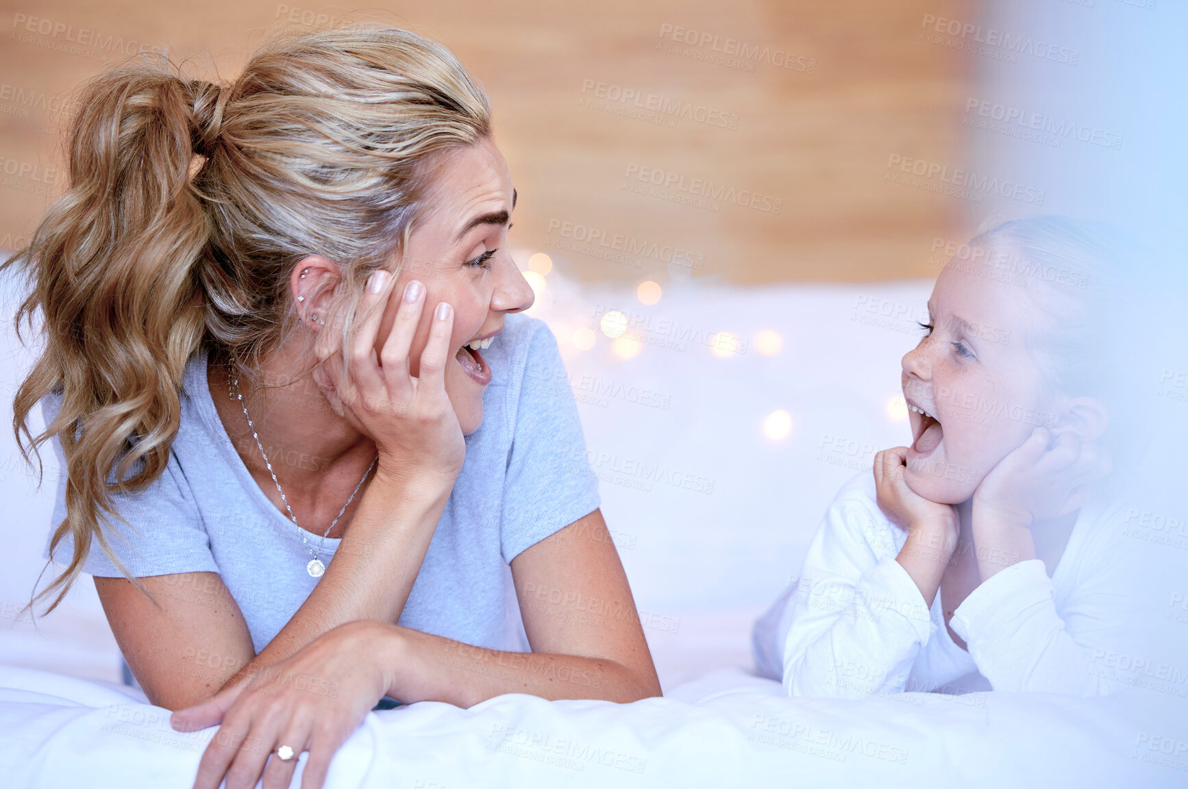 Buy stock photo Happy caucasian mother and daughter lying on a bed at home. Cheerful woman with cute little girl enjoying a cosy and lazy relaxing day together. Loving parent bonding and sharing quality time with kid