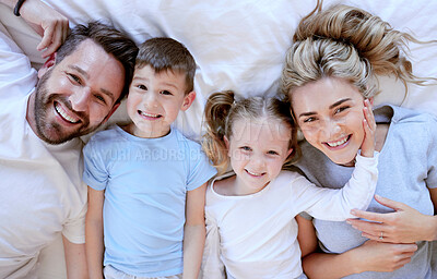 Portrait of happy carefree caucasian family in pyjamas from above lying cosy in bed at home. Loving parents spending quality time with son and daughter. Cute kids enjoy lazy morning with mom and dad