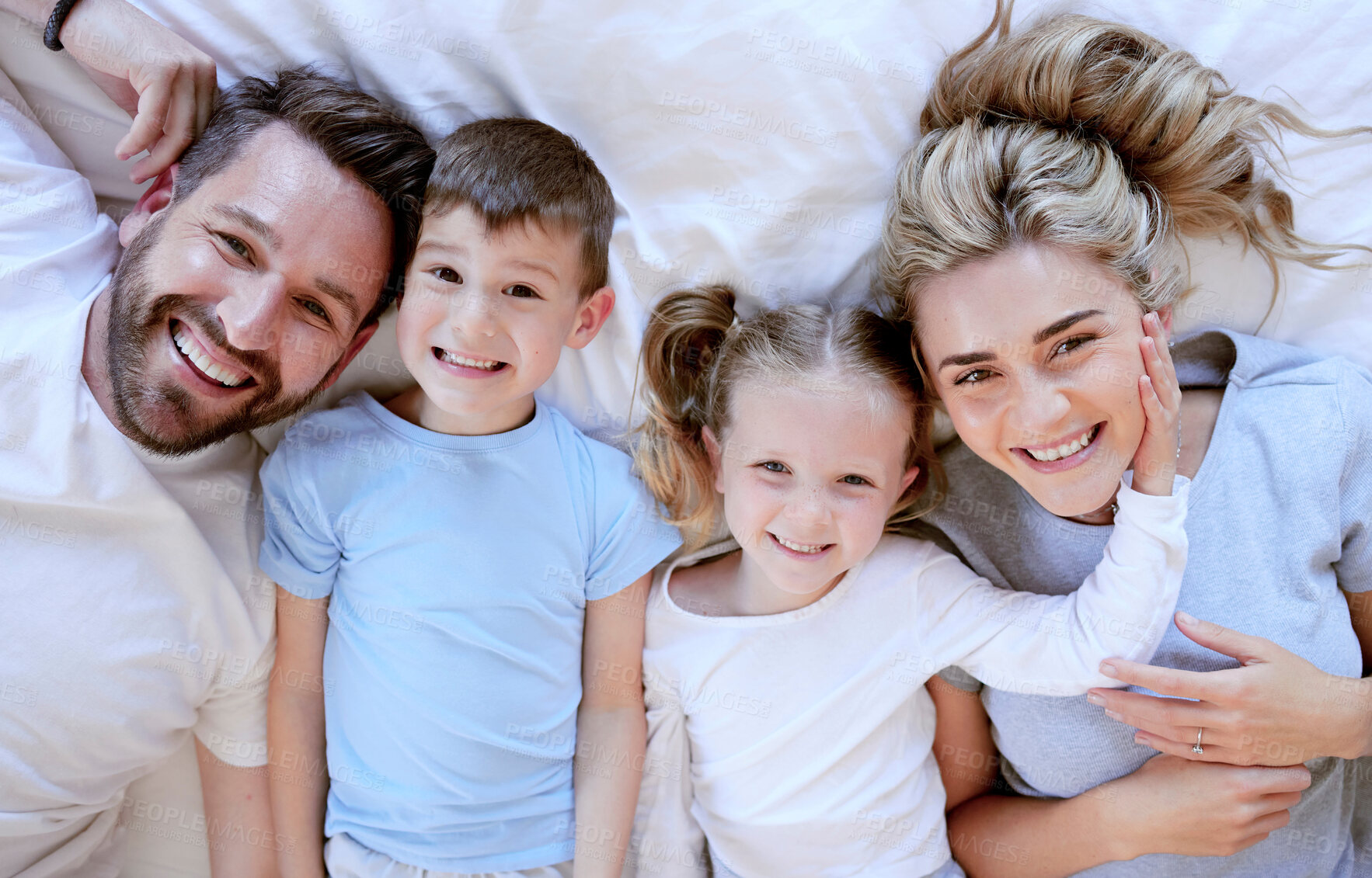 Buy stock photo Portrait of happy carefree caucasian family in pyjamas from above lying cosy in bed at home. Loving parents spending quality time with son and daughter. Cute kids enjoy lazy morning with mom and dad
