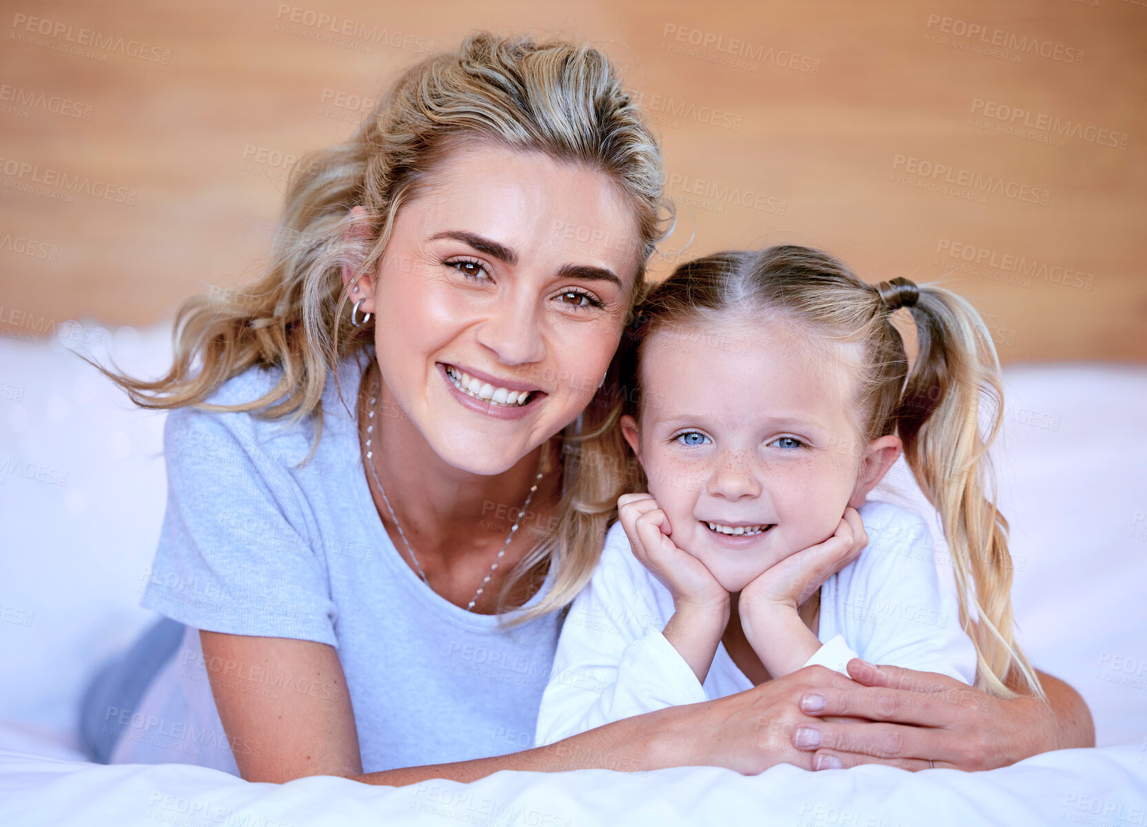 Buy stock photo Portrait of happy caucasian mother and daughter lying on bed at home. Cheerful woman with little girl enjoying a cosy and lazy relaxing day. Loving parent bonding and sharing quality time with kid
