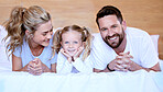 Happy parents with little daughter lying on bed at home. Smiling caucasian girl bonding and enjoying free time with her mother and father on the weekend. Young husband and wife with their only child