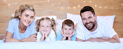 Buy stock photo Portrait of a young family lying in bed. Married couple enjoying free time with their son and daughter at home. Adorable little girl and boy bonding with their mother and father in the morning