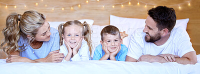 Happy carefree caucasian family lying cosy on bed while bonding together at home. Loving parents spending quality time with little son and daughter. Cute kids enjoying lazy morning with mom and dad
