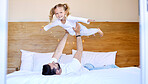 Adorable little girl bonding with her single father at home and pretending she can fly. Caucasian single parent holding and lifting his daughter in the air. Smiling child playing in the bedroom 